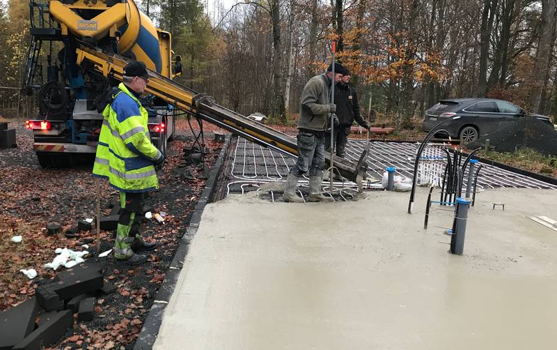 One man controlling the concrete flow and two men making sure it's levelled off correctly.