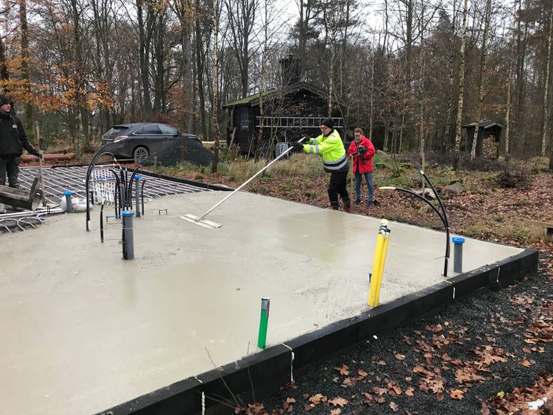 One man with a large concrete trowel smoothing the surface of the concrete.