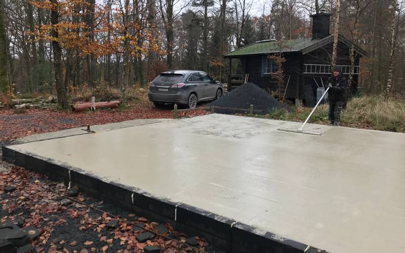 Man using a concrete trowel to smoothen the surface of the concrete slab.