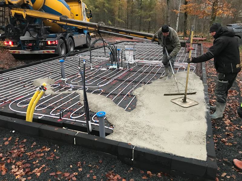 Two men raking and levelling off the concrete.